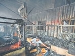 A labourer searches through the debris after a fire gutted container-based temporary residences of workers at a construction site near Udyog Bhawan on Wednesday. (Arvind Yadav/HT PHOTO)