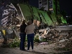 People wait at the site of a collapsed building as emergency workers search for survivors after an earthquake in Caracas, Venezuela, 