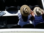 Two women sitting in a touristic boat on the river Spree shelter from sun with large sunheats in the center of Berlin on June 26, 2026. 