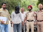 Sandeep Singh, 23, (face covered), the third accused involved in the petrol bomb attack, in police custody in Bathinda on Saturday. (Sanjeev Kumar/HT)