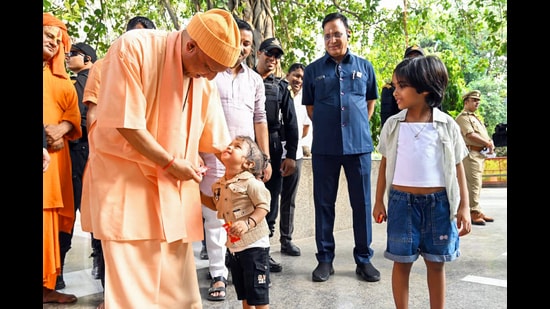 Chief minister Yogi Adityanath gives chocolate to a child during the 'Janta Darshan' at the Gorakhnath Temple premises, in Gorakhpur on Saturday. (@CMOfficeUP X)