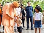 Chief minister Yogi Adityanath gives chocolate to a child during the 'Janta Darshan' at the Gorakhnath Temple premises, in Gorakhpur on Saturday. (@CMOfficeUP X)
