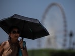 A tourist with an umbrella walks in Paris during a heat wave.