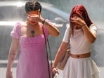 Youngsters walk by a water mist machine installed by city administration to assist people in coping with the heat on a torrid day, as the National Weather forecaster issued an extreme heat code red warning for most parts of the country, in Bucharest, Romania, Monday, June 29, 2026. (AP Photo/Vadim Ghirda)
