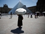 A person protects from the sun under an umbrella in front of the Louvre museum in Paris as a record-breaking early heatwave scorches a swathe of western Europe on May 28, 2026. 