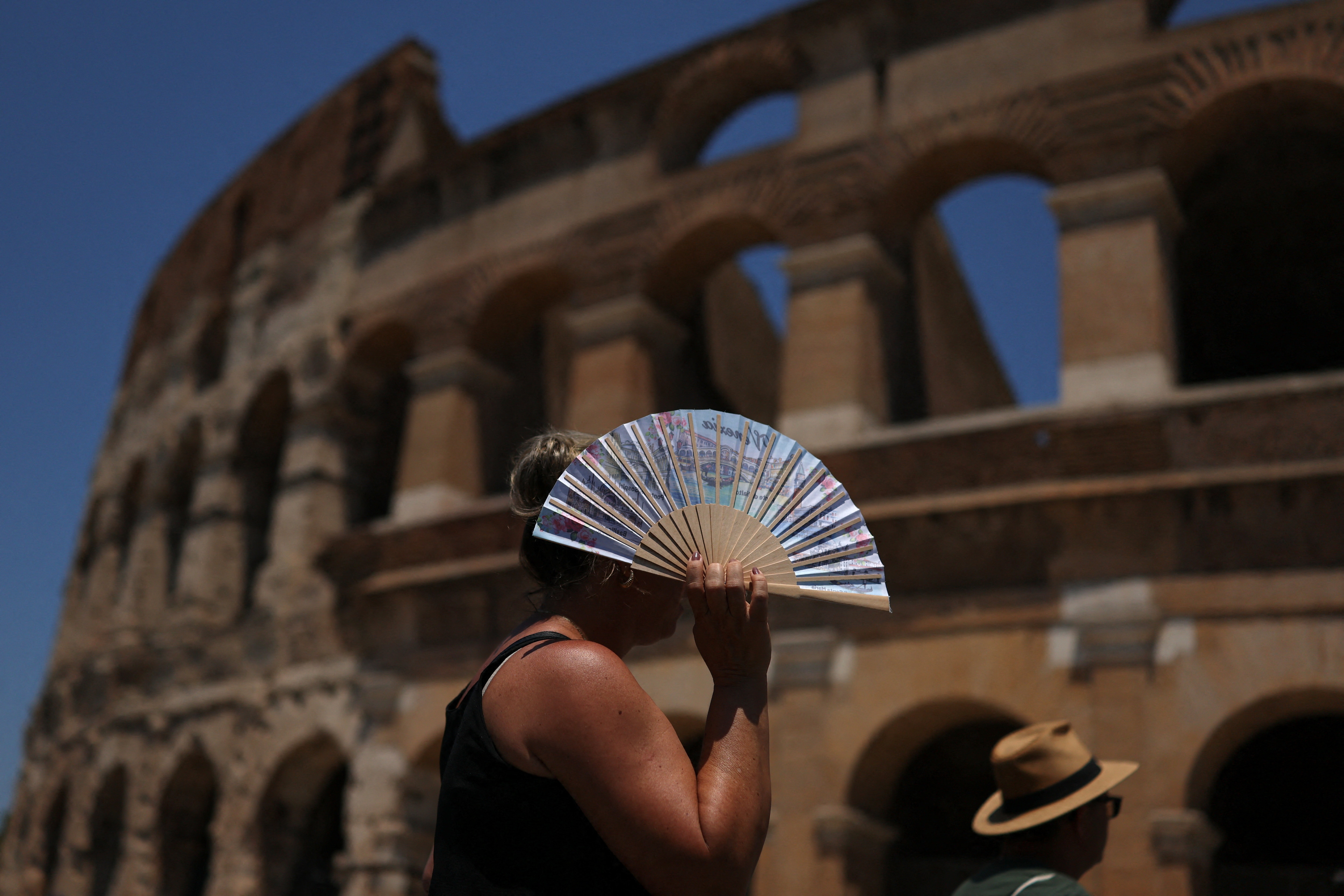 A woman uses a fan to shelter from the sun outside the Colosseum during a heatwave in Rome, Italy. (REUTERS)