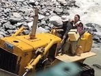 Health worker Paljom Butti crossing the stream on bulldozer in Lahaul-Spiti on Sunday. (Screen grab)