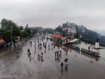 Tourists cover themselves with umbrellas as they walk amid rain on The Ridge in Shimla on Monday. (ANI Photo)