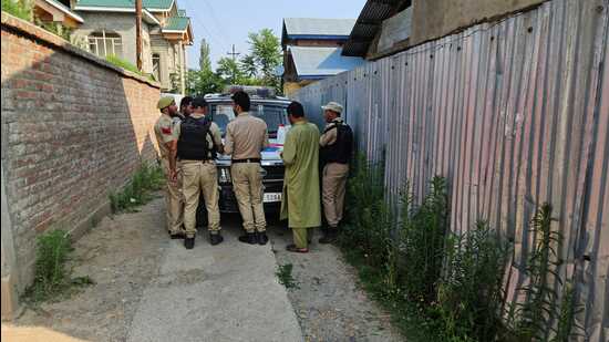 Police standing outside the house of PDP district president, Baramulla, Mohammad Rafique Rather, on Tuesday. (HT Photo)