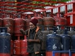 A delivery worker stands atop a truck carrying LPG cylinders at a distribution point in Bengaluru. (AFP)