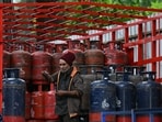 A delivery worker stands atop a truck carrying LPG cylinders at a HP Gas distribution point in Bengaluru.