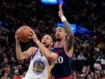 Golden State Warriors guard Stephen Curry, left, shoots as LA Clippers forward John Collins defends during the first half of an NBA play-in tournament basketball game.