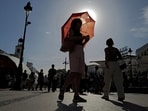 A woman with an umbrella walks at Plaza Puerta del Sol during a spring heatwave in Madrid, Spain.(REUTERS)