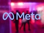 People walk behind a logo of Meta Platforms company, during a conference in Mumbai, India.