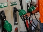 A petrol pump attendant picks up a nozzle to refuel a vehicle.