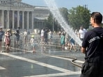 A firefighter uses water cannon to spray residents at Heroes Square to help them cool off during a severe heatwave in Budapest, Hungary