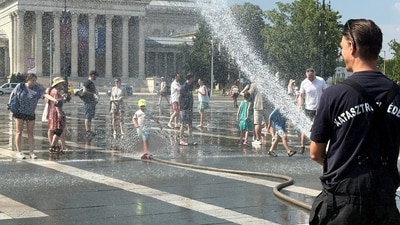 A firefighter uses water cannon to spray residents at Heroes Square to help them cool off during a severe heatwave in Budapest, Hungary (REUTERS)