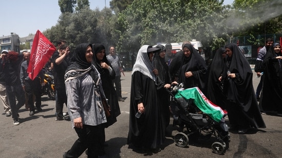 Iran US war update LIVE: People cool themselves under a water sprinkler as they attend a public farewell ceremony to pay their respects to the late Supreme Leader Ayatollah Ali Khamenei.