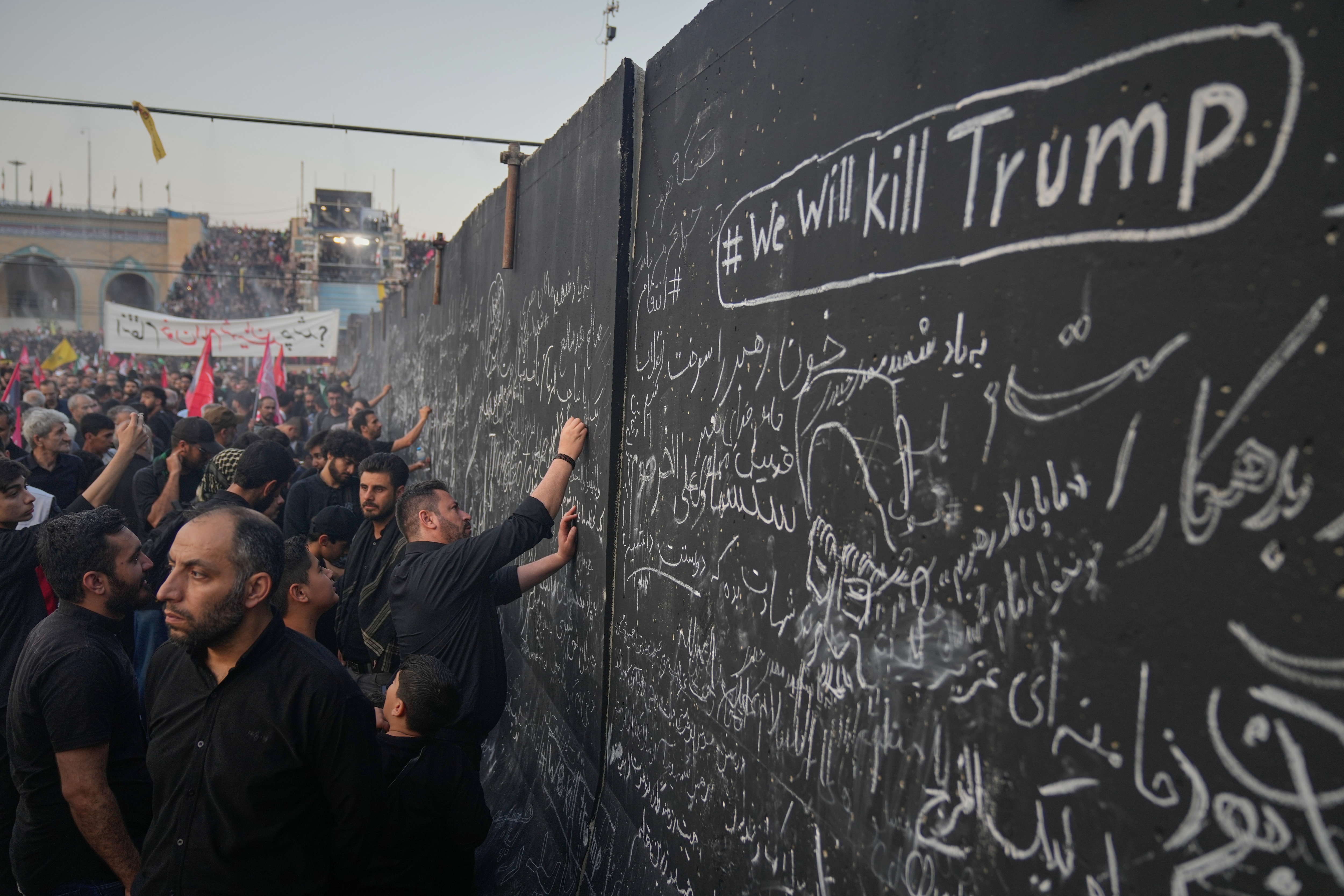 Mourners write messages on a wall, including one in English that reads "We will kill Trump," during the funeral ceremonies for slain Iranian Supreme Leader Ayatollah Ali Khamenei and members of his family at the Imam Khomeini Mosalla Grand Mosque in Tehran, Iran, Saturday, July 4, 2026. (AP/Altaf Qadri)