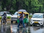 New Delhi, Jul 05 (ANI): A man holding umbrella walks on a zebra crossing amid rain, in New Delhi on Sunday. (ANI Photo/Jitender Gupta)