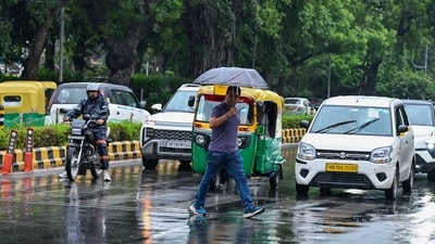 New Delhi, Jul 05 (ANI): A man holding umbrella walks on a zebra crossing amid rain, in New Delhi on Sunday. (ANI Photo/Jitender Gupta) (Jitender Gupta)