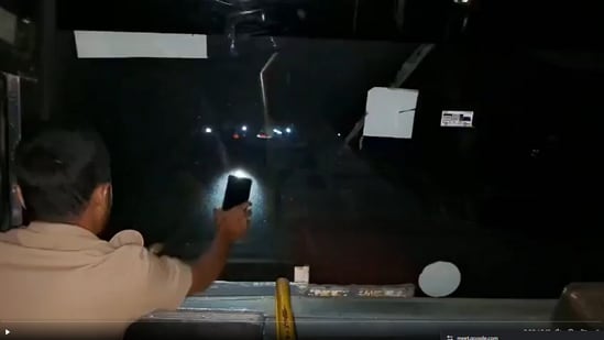 While the driver steers the bus, the conductor is seen using the torchlight of a mobile phone to illuminate the road ahead. (X/Nikhil_Kumar_k)