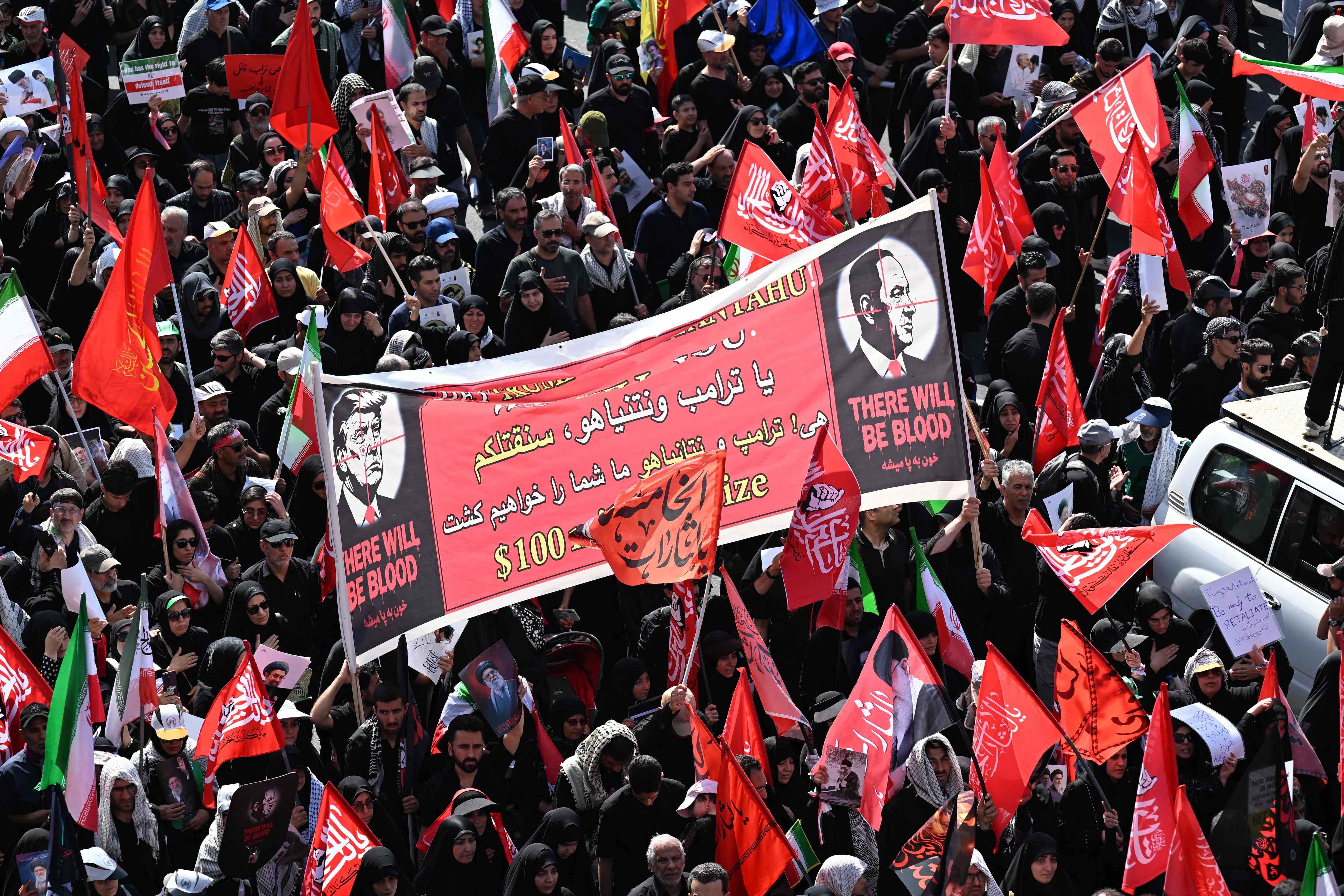 People hold a banner depicting US President Donald Trump and Israel's Prime Minister Benjamin Netanyahu displaying the words "There Will Be Blood" as they gather along a street for the funeral in Tehran. (AFP) People hold a banner depicting US President Donald Trump and Israel's Prime Minister Benjamin Netanyahu displaying the words "There Will Be Blood" as they gather along a street for the funeral in Tehran. (AFP)