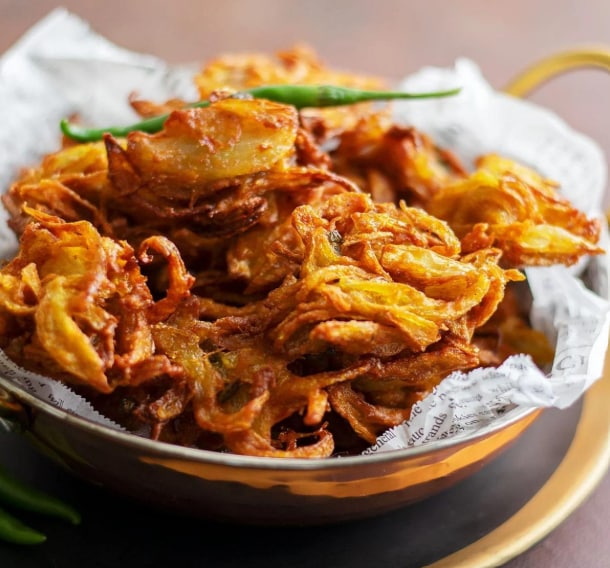 A beloved monsoon classic, Onion Bhajiya is made with thinly sliced onions coated in a spiced gram flour batter and deep-fried until crisp and golden. Best enjoyed with hot chai and green chutney on a rainy evening. (Picture credit: Chef Evangelist JP) A beloved monsoon classic, Onion Bhajiya is made with thinly sliced onions coated in a spiced gram flour batter and deep-fried until crisp and golden. Best enjoyed with hot chai and green chutney on a rainy evening. (Picture credit: Chef Evangelist JP)