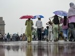 People shield themselves from the rain near India Gate in New Delhi. (PTI)