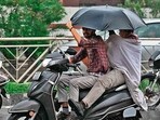 Scooterists carrying umbrella amid rainfall in Amritsar. (AFP)