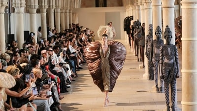 A dramatic bronze sculptural gown brought theatrical grandeur to the runway, juxtaposed against models styled as ancient temple statues. (AFP)