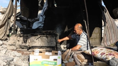 A displaced Palestinian man tends a makeshift oven inside a shelter near the al-Shati refugee camp, west of Gaza City. (AFP)
