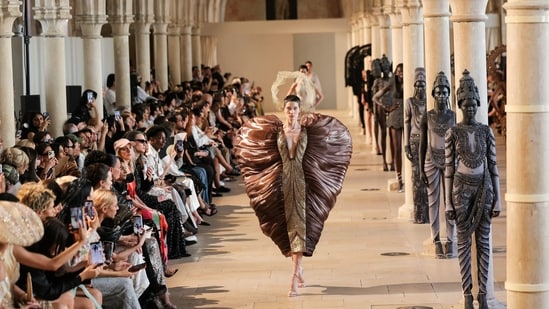 A dramatic bronze sculptural gown brought theatrical grandeur to the runway, juxtaposed against models styled as ancient temple statues.(AFP)