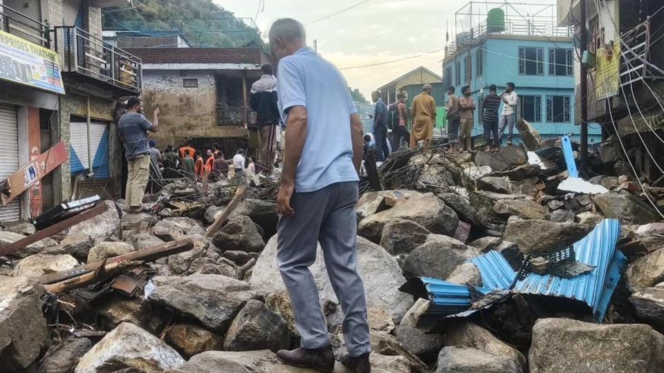 Residents walking through the rubble after the flash flood brought boulders down the hill into the town of Thathri in Doda district on Tuesday. (PTI Photo)