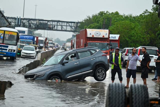 A car stuck in a storm water drain along National Highway 48 near Narsinghpur village on Tuesday. (Parveen Kumar/HT) A car stuck in a storm water drain along National Highway 48 near Narsinghpur village on Tuesday. (Parveen Kumar/HT)
