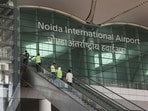 People stand on an escalator as they enter Noida International Airport (NIA), in Noida.