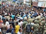 Security personnel stand guard as people block a road and stage a protest following the recovery of the body of an 11-year-old girl who went missing a day ago, in Baruipur, South 24 Parganas district, West Bengal, on Sunday, July 5