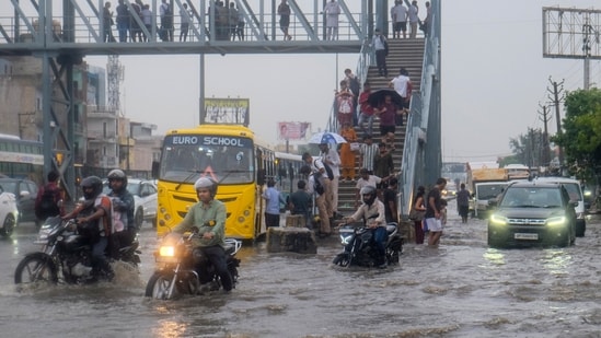 Commuters wade through a severely waterlogged road following heavy rainfall, in Gurugram, Haryana, Tuesday, July 7, 2026. (PTI)
