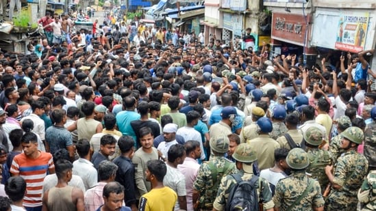 Security personnel stand guard as people block a road and stage a protest following the recovery of the body of an 11-year-old girl who went missing a day ago, in Baruipur, South 24 Parganas district, West Bengal, on Sunday, July 5 (PTI)