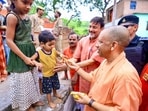 Chief minister Yogi Adityanath offers a chocolate to a child during his visit to Kamadgiri mountain, in Chitrakoot district, on Thursday. (PTI Photo)