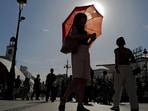 A woman with an umbrella walks at Plaza Puerta del Sol during a spring heatwave in Madrid, Spain.