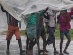People shield themselves from heavy showers in Agartala, Tripura, on Wednesday. (PTI)