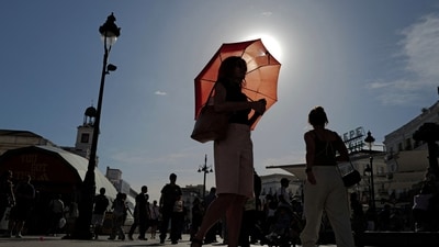 A woman with an umbrella walks at Plaza Puerta del Sol during a spring heatwave in Madrid, Spain. (REUTERS)