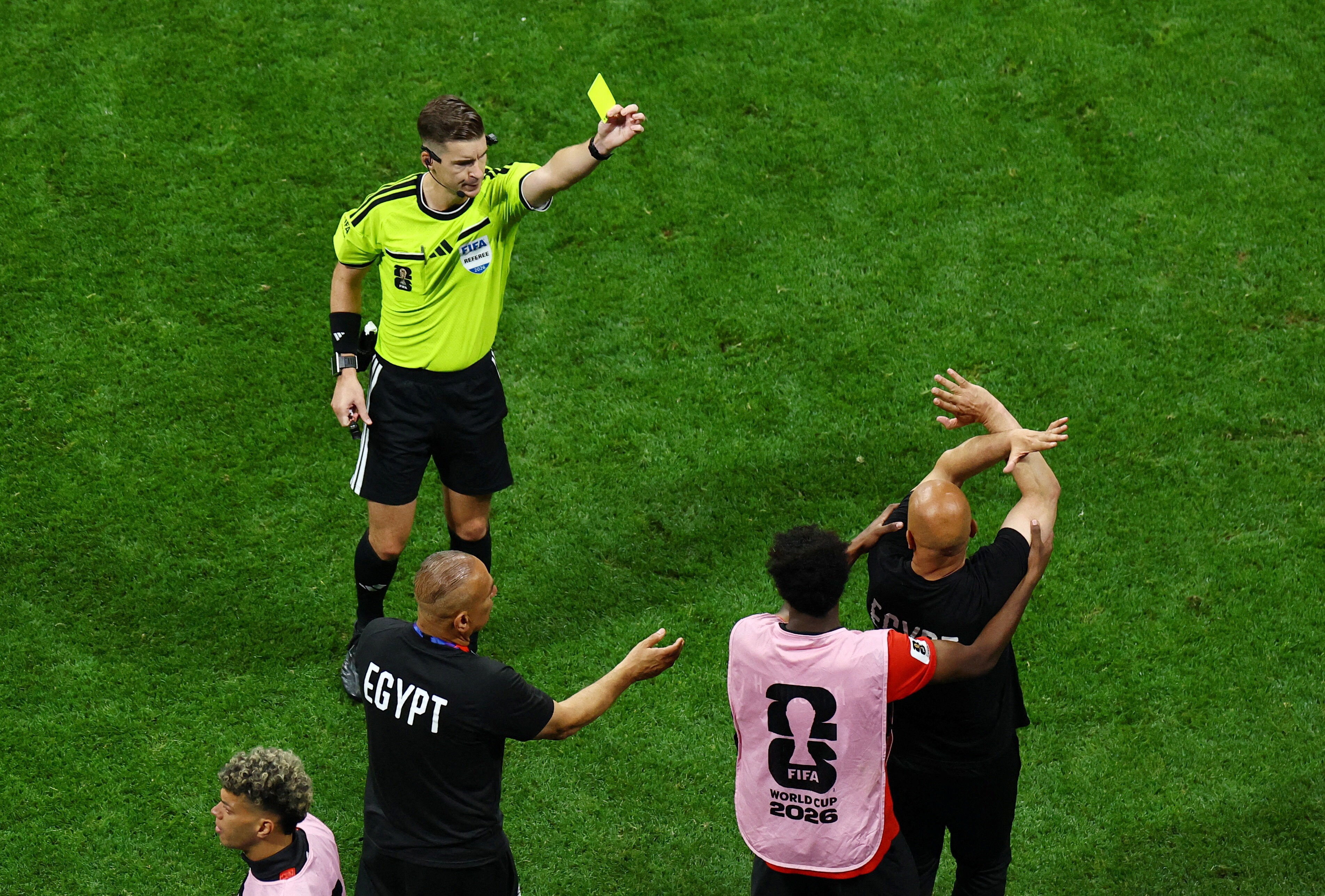 Egypt coach Hossam Hassan is shown a yellow card by referee Francois Letexier as he makes anti-racism gesture (Reuters)