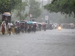 Commuters wade through a waterlogged road following heavy rains in Delhi NCR.