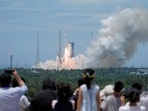 People watch as a Long March 10B carrier rocket takes off from Wenchang Spacecraft Launch Site, before returning vertically to an offshore platform for a controlled recovery, in Hainan province, China 
