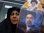 A woman holds a portrait of Iran's Supreme Leader Mojtaba Khamenei and Iran’s late Supreme Leader Ayatollah Ali Khamenei as mourners gather during funeral ceremonies in Karbala, Iraq.