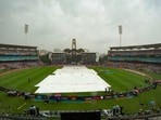Navi Mumbai: Groundsmen cover the field amid rain at the DY Patil Stadium