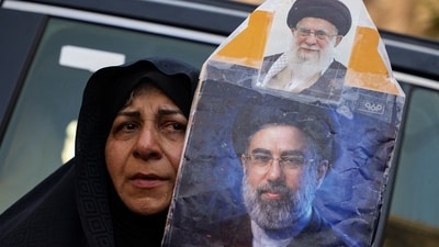 A woman holds a portrait of Iran's Supreme Leader Mojtaba Khamenei and Iran’s late Supreme Leader Ayatollah Ali Khamenei as mourners gather during funeral ceremonies in Karbala, Iraq. (REUTERS)