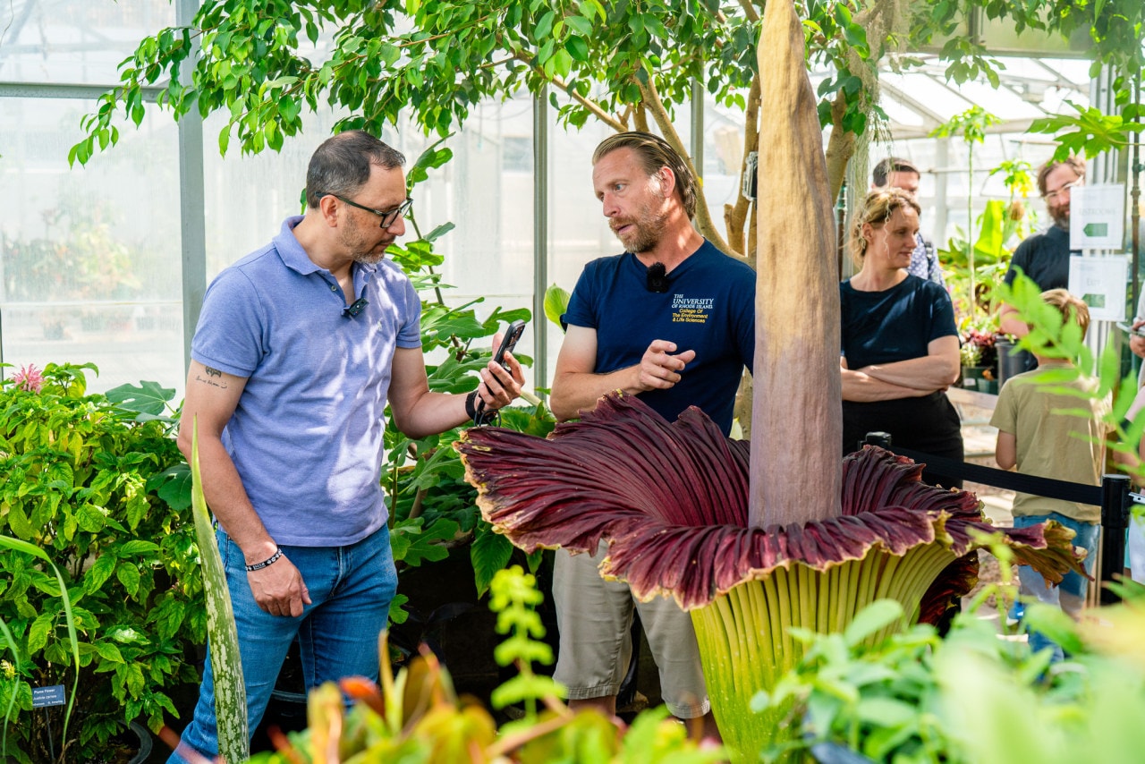 Ben Robbins, manager at URI's greenhouse, speaks with visitors of Morticia.